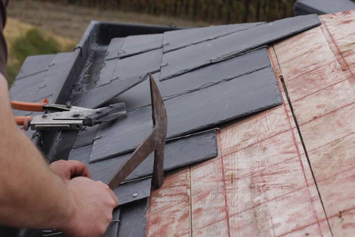 Man using tools to remove roofing slates